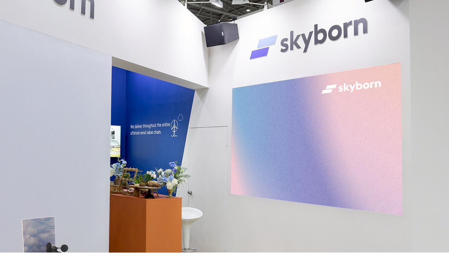 Skyborn 展場現場：藍粉漸層光譜螢幕與壓克力風能裝置，呈現品牌主視覺。