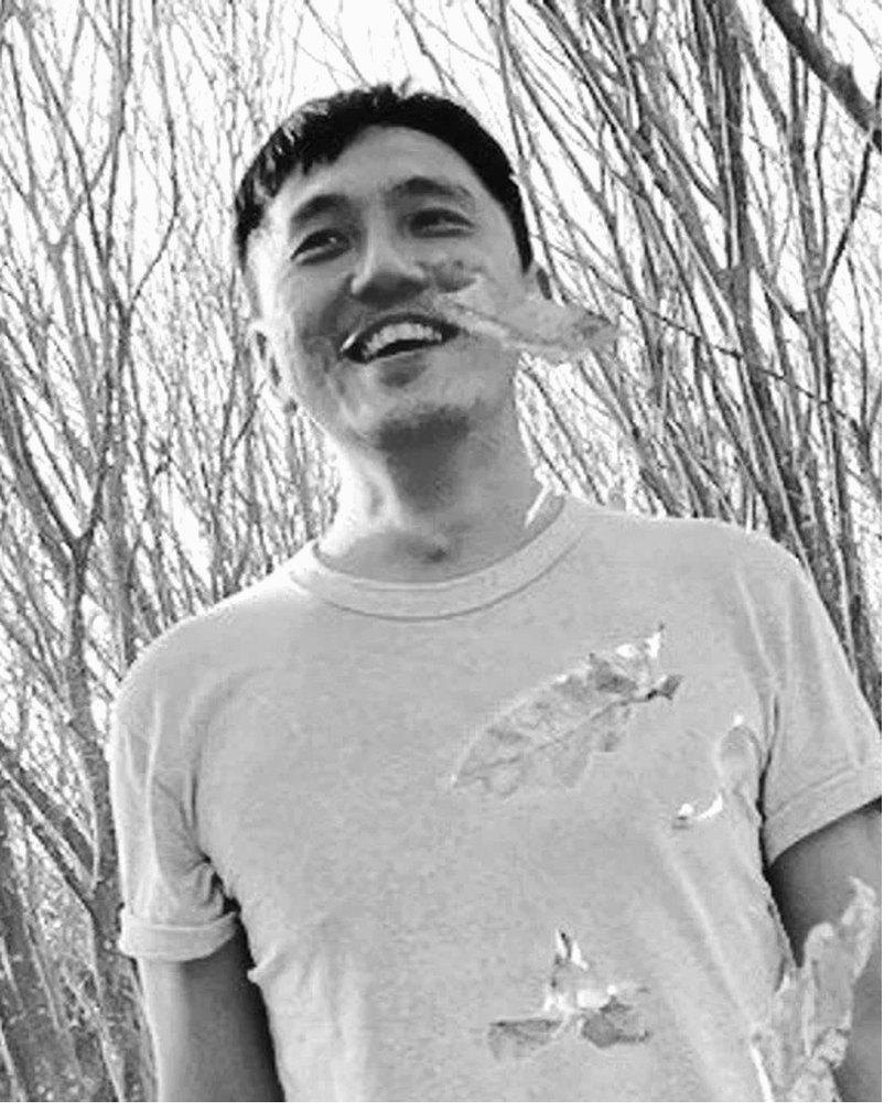 Mike Chen,Acorn 核心成員。黑白肖像,身穿淺色 T 恤站在乾燥枝枒前,笑容自然開朗。